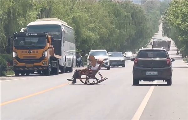 大爷马路中间手拿折扇躺摇椅上晒太阳 过往车辆纷纷减速避让